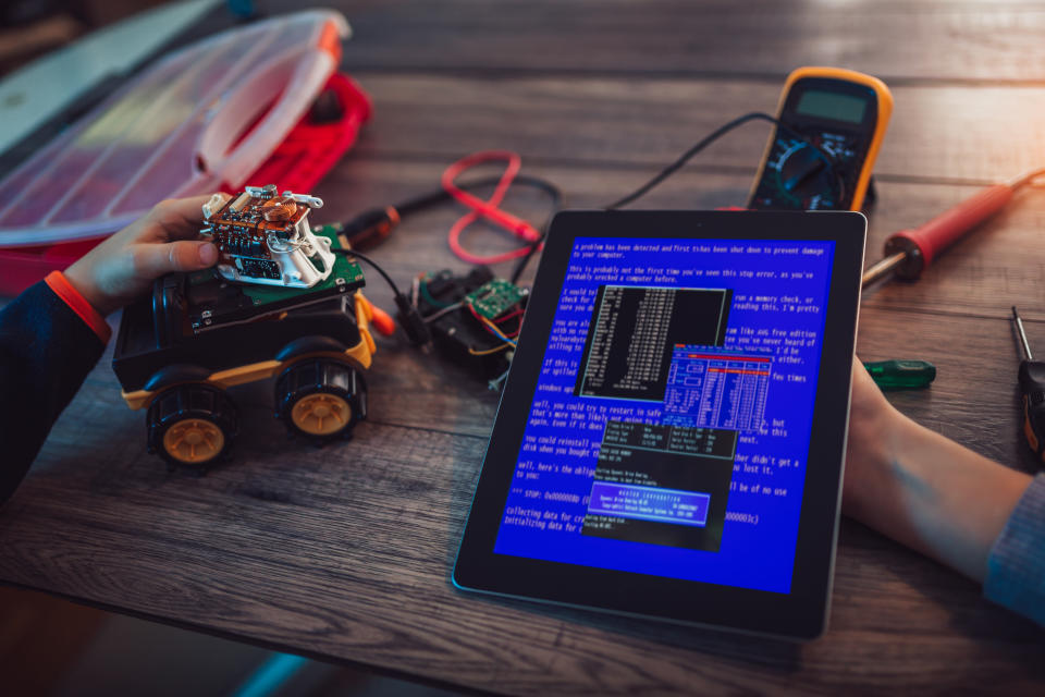 Schoolchildren programming robot together and using digital tablet during STEM educational class