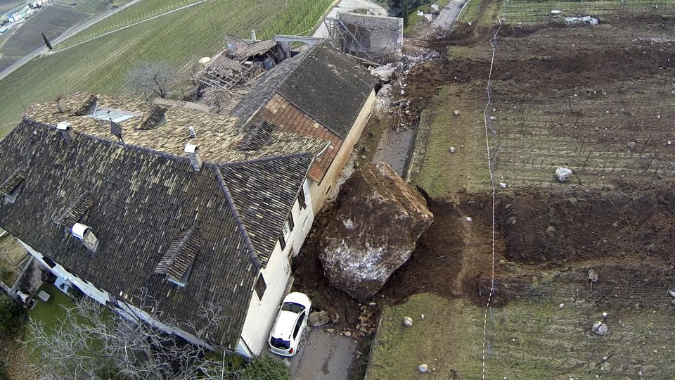 In this photo provided by Tareom.com Thursday, Jan. 30, 2014, and taken on Jan. 23, 2014, a huge boulder is seen after it stopped next to a farm house, while a second giant boulder, which detached during the same landslide on Jan. 21, 2014, whose trail can be seen on top, missed the house by less than a meter, destroying the barn, and stopped in the vineyard below, in Ronchi di Termeno, in Northern Italy. According to reports, the Trebo family living there was unharmed in the landslide. (AP Photo/Markus Hell, Tareom.com, ho)