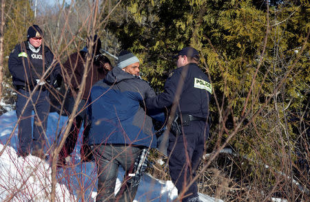 A man who claimed to be from Sudan looks back after being detained by Royal Canadian Mounted Police (RCMP) officers after running across the U.S.-Canada border into Hemmingford, Canada, from Champlain in New York, U.S., February 17, 2017. REUTERS/Christinne Muschi