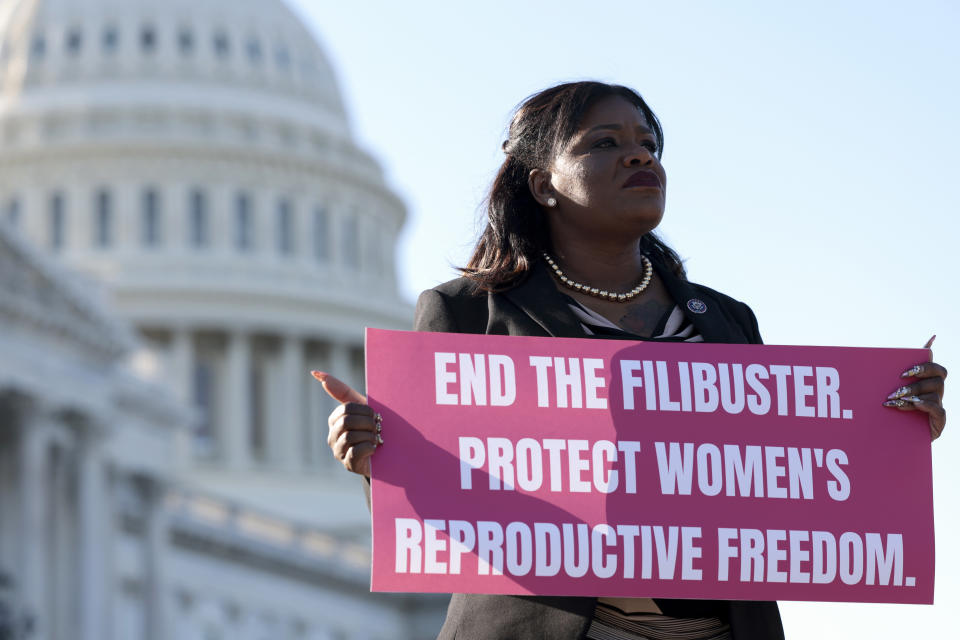 Rep. Cori Bush stands outside the Capitol holding a sign that reads: End the filibuster. Protect women’s reproductive freedom.