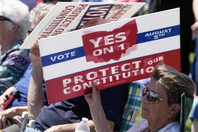 <p>Darron Cummings/AP Photo</p> An attendee uses a sign to shield the sun during an August rosary rally aimed at promoting Ohio's Issue One