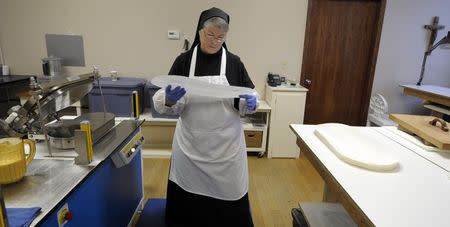 Sister Rebecca Leis inspects a baked sheet of low-gluten alter bread at the Benedictine Sisters of Perpetual Adoration monastery in Clyde Missouri December 18, 2014. REUTERS/Dave Kaup