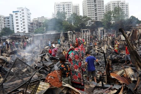 Slum dwellers are seen gather near their shelters after fire burnt them out in Dhaka