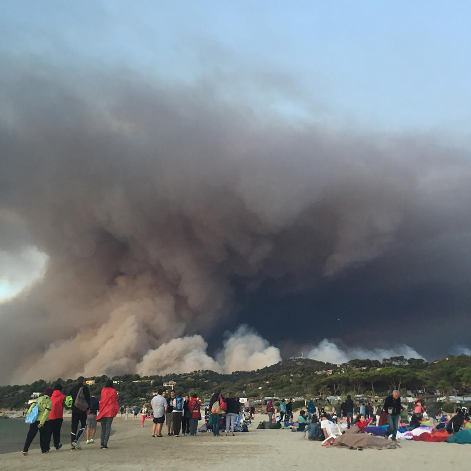 <p>People watch as smoke billows from a fire, in Bormes-les-Mimosas, France July 26, 2017 in this picture obtained from social media. (Anna Tomlinson/Reuters) </p>