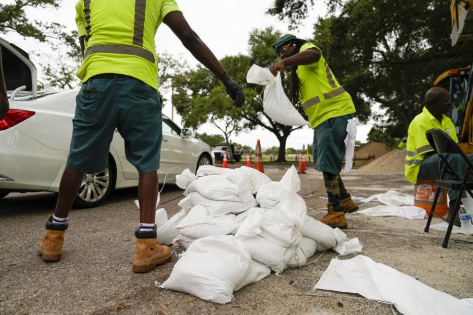 City employees load sandbags into people’s cars as they pull up to a station at Northwest Park, in preparation for Hurricane Ian.