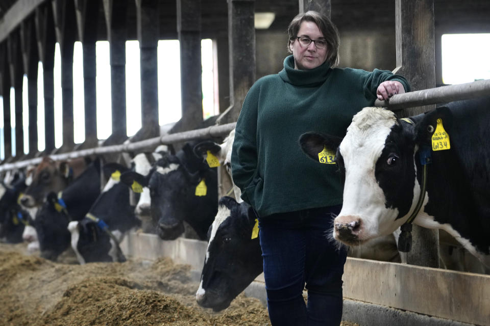 Jenni Tilton-Flood poses for a photograph in a dairy barn at Flood Brothers Farm, Wednesday, March 27, 2024, in Clinton, Maine. Foreign-born workers make up fully half the farm's staff of nearly 50, feeding the cows, tending crops and helping collect the milk — 18,000 gallons every day. (AP Photo/Robert F. Bukaty)