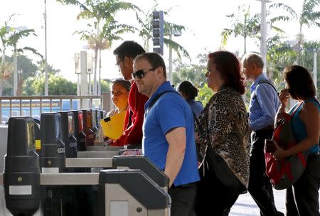 Riders of Miami's Metrorail system walk through turnstiles in Miami, Florida November 5, 2015. REUTERS/Joe Skipper