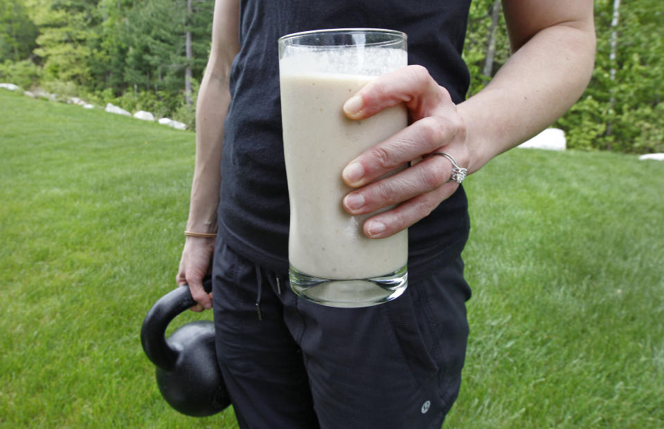 In this image taken on Tuesday, May 15, 2012, Amanda Perry holds a protein shake for lunch and a kettleball as she poses at her home in Tyngsborough, Mass. Perry, a gym owner and personal trainer, blends a vegan protein powder with almond milk, natural peanut butter, ice and a banana as a drink in her daily diet. A surge in protein as both a nutrient and a marketing element has been added to the American diet. (AP Photo/Charles Krupa)