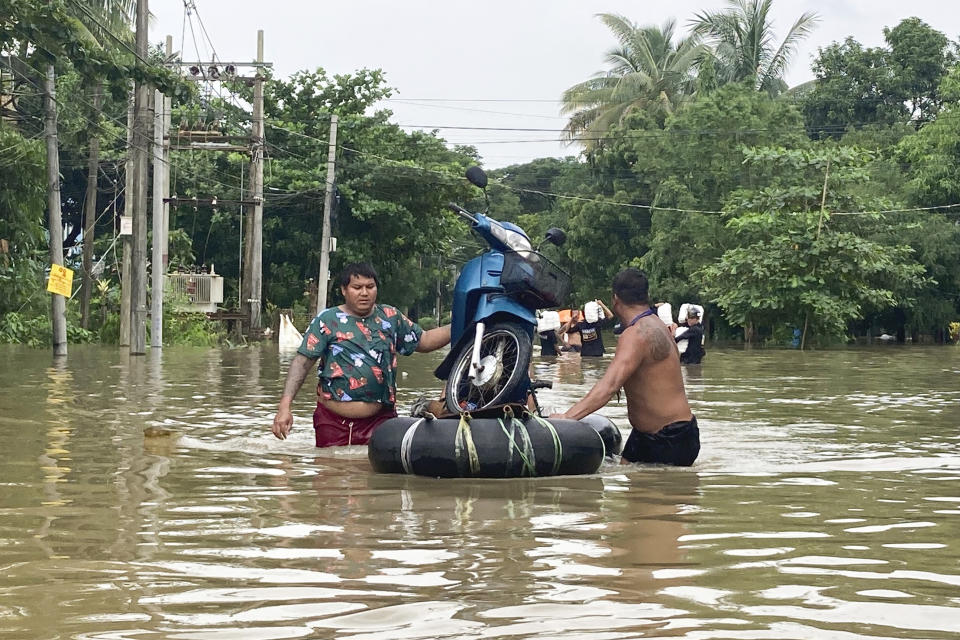 Local residents push a motorbike on a make-shift raft made of inner-tubes down a flooded road in Bago, Maynmar, about 80 kilometers (50 miles) northeast of Yangon, Friday, Aug. 11, 2023. (AP Photo)