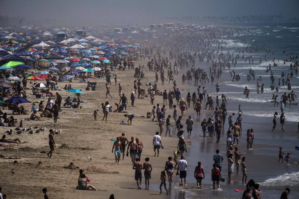 People crowd the beach in Huntington Beach, Calif., on Labor Day weekend, seeking relief from a dangerous and record-setting heatwave but risking the spread of coronavirus.