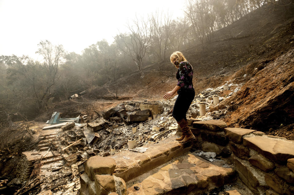 Pam, who declined to give a last name, examines the remains of her partner's Vacaville, Calif., home on Friday, Aug. 21, 2020. The residence burned as the LNU Lightning Complex fires ripped through the area Tuesday night. (AP Photo/Noah Berger)