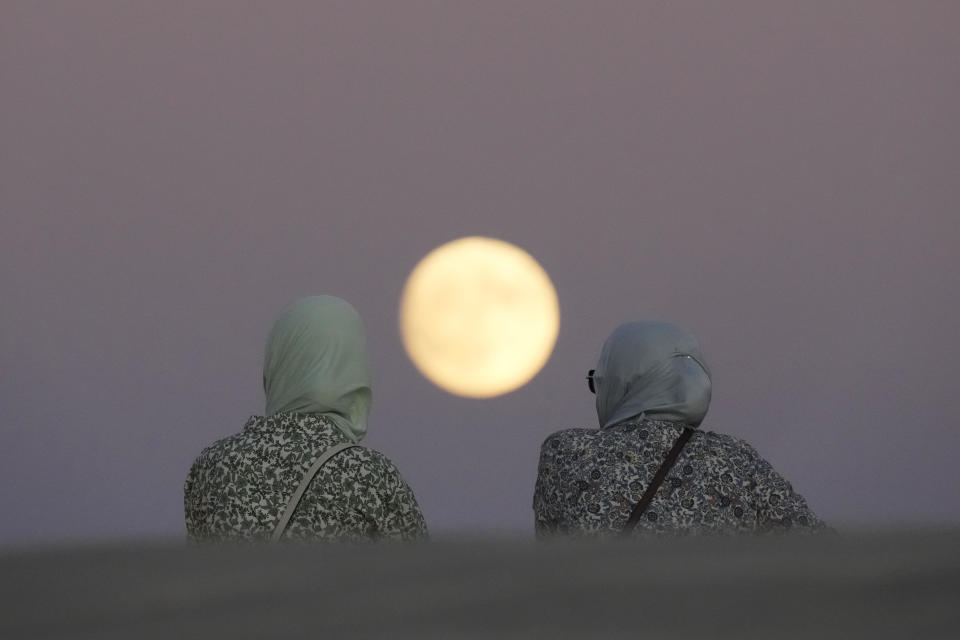 Two women watch the near-full supermoon appear over the Tagus River from the roof of the Museum of Art, Architecture and Technology in Lisbon, Portugal, Aug. 18, 2024. / Copyright Armando Franca/AP