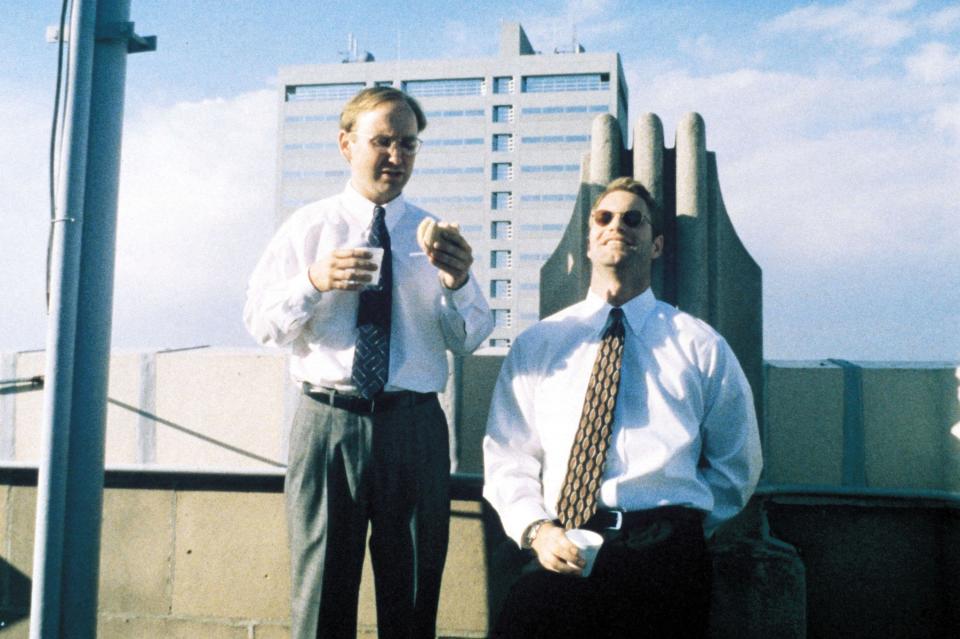 Two men in business suits enjoy coffee and breakfast on a roof