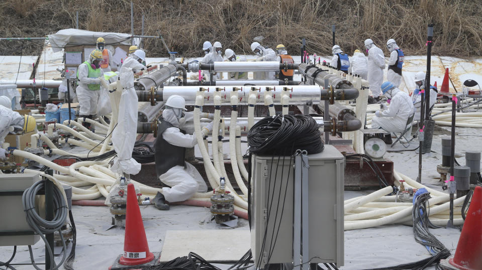 FILE - In this March 10, 2014 file photo, workers of the Tokyo Electric Power Co. (TEPCO) wearing protective gears install an underground frozen wall during a feasibility test at the Fukushima Dai-ichi nuclear power plant in Okuma town, Fukushima prefecture, northeastern Japan. Experts said Friday they are skeptical about a plan to build a costly underground frozen wall at Japan’s crippled nuclear plant, a development that could delay construction plans. The experts and Japanese nuclear regulatory officials said during a meeting Friday, May 2 they weren’t convinced the project can resolve the contaminated water problem at the Fukushima Dai-ichi plant, which suffered meltdowns following the 2011 earthquake and tsunami. (AP Photo/Koji Sasahara, Pool)