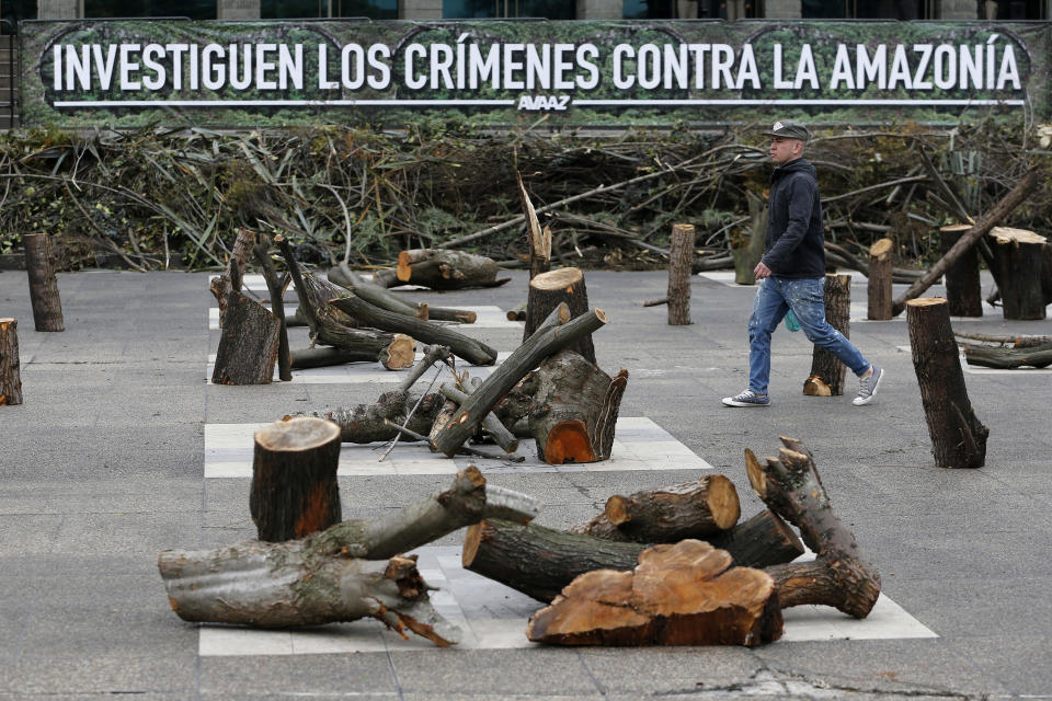 FILE - A pedestrian walks past branches and trunks in Bogota, Colombia, Sept. 12, 2018, in front of the Attorney General's Office, placed there by activists as a form of protest denouncing the deforestation of the Amazon rainforest. Gustavo Petro, Colombia's first elected leftist president, will take office in August with ambitious proposals to halt the record-high rates of deforestation in the Amazon. (AP Photo/Fernando Vergara, File)