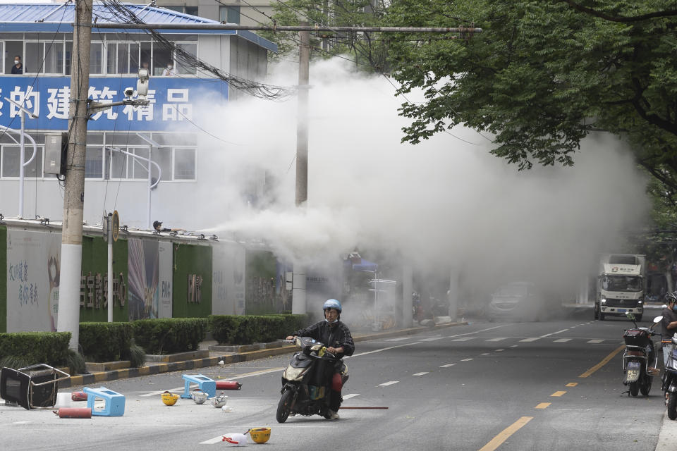 A rider past by helmets and plastics thrown out by workers at a construction site who also sprayed unknown gas to protest their continued quarantine in Shanghai on Friday, May 27, 2022. Residents in China's largest city of Shanghai have become bolder in demanding the lifting or easing of coronavirus restrictions that have left millions locked up in their compounds for almost two months. (AP Photo/Andrew Braun)