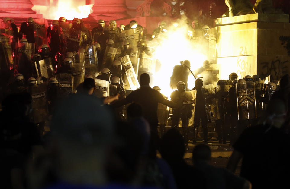 Protesters clash with riot police on the steps of the Serbian parliament during a protest in Belgrade, Serbia, Friday, July 10 2020. Hundreds of demonstrators tried to storm Serbia's parliament on Friday, clashing with police who fired tear gas during the fourth night of protests against the president's increasingly authoritarian rule. (AP Photo/Darko Vojinovic)