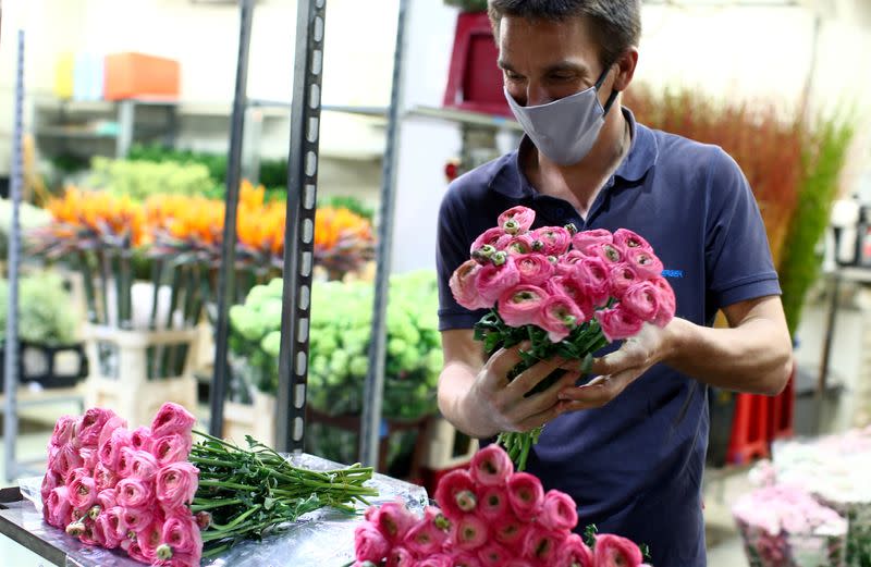 A seller wears a protective mask as he prepares flowers for sale at the central flower market (Grossgruenmarkt) in Vienna