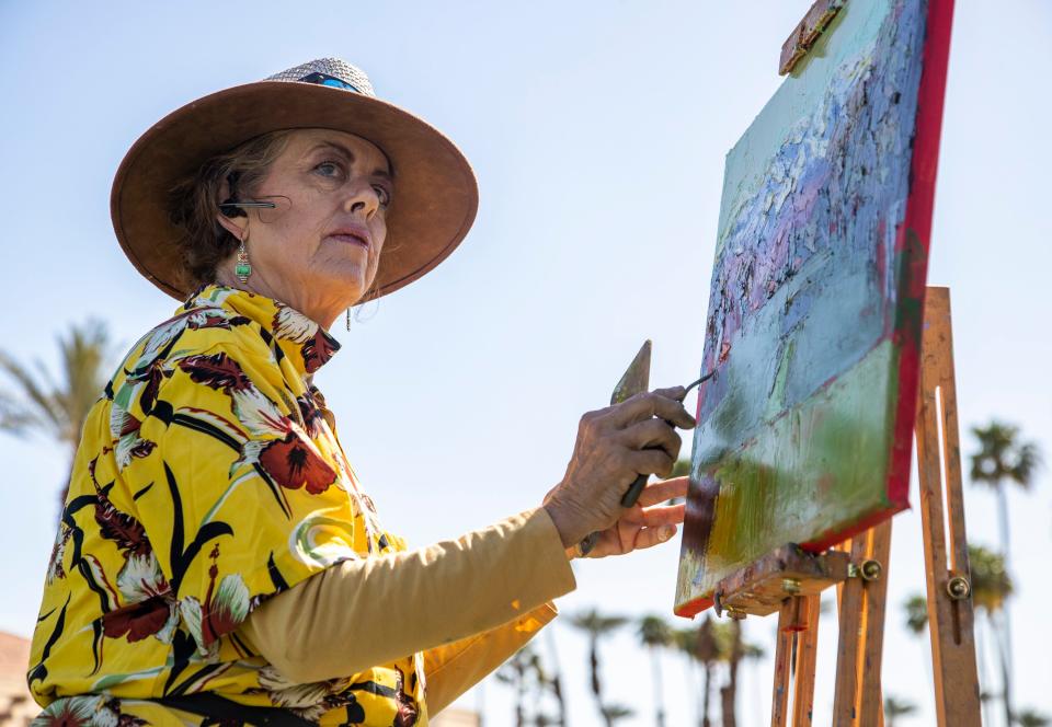 Artist Kathleen Strukoff looks toward the first tee while painting a view of it with the snow-capped San Jacinto mountains in the distance during the first round of the Galleri Classic in Rancho Mirage on Friday.