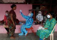 A health worker in personal protective equipment (PPE) checks the temperature of a resident with an electronic thermometer during a check up campaign for the coronavirus disease (COVID-19), in Mumbai