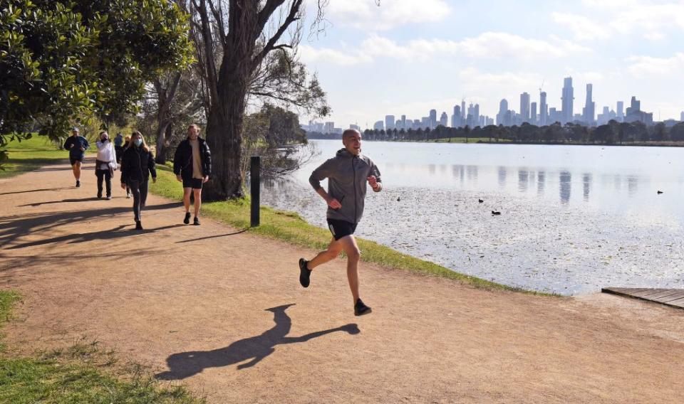 A jogger runs beside Albert Park Lake in Melbourne.