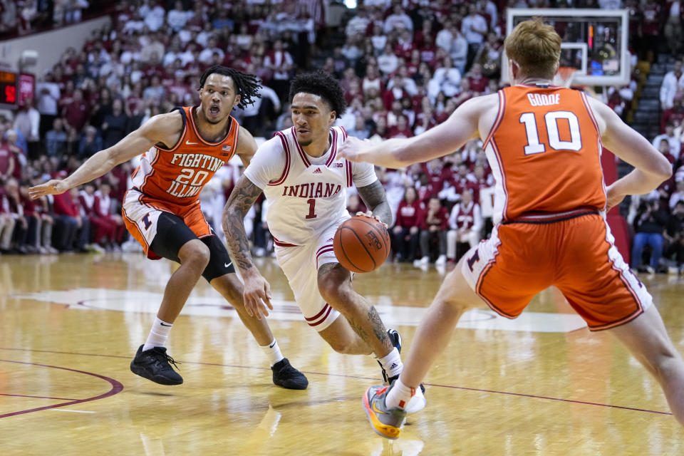 Indiana guard Jalen Hood-Schifino (1) drives between Illinois forward Ty Rodgers (20) and guard Luke Goode (10) in the second half of an NCAA college basketball game in Bloomington, Ind., Saturday, Feb. 18, 2023. Indiana defeated Illinois 71-68. (AP Photo/Michael Conroy)