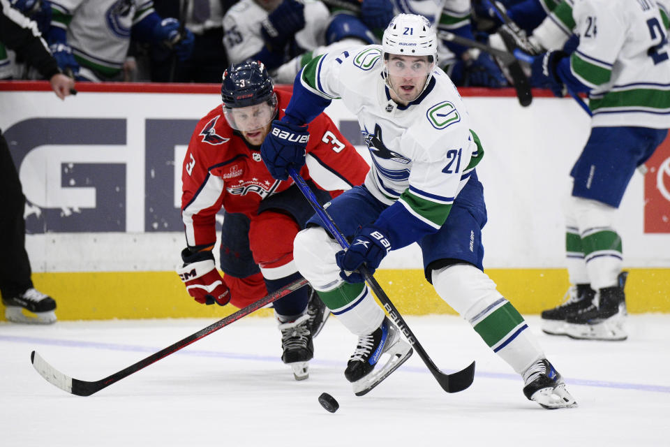 Vancouver Canucks left wing Nils Hoglander (21) skates with the puck past Washington Capitals defenseman Nick Jensen (3) during the second period of an NHL hockey game, Sunday, Feb. 11, 2024, in Washington. (AP Photo/Nick Wass)