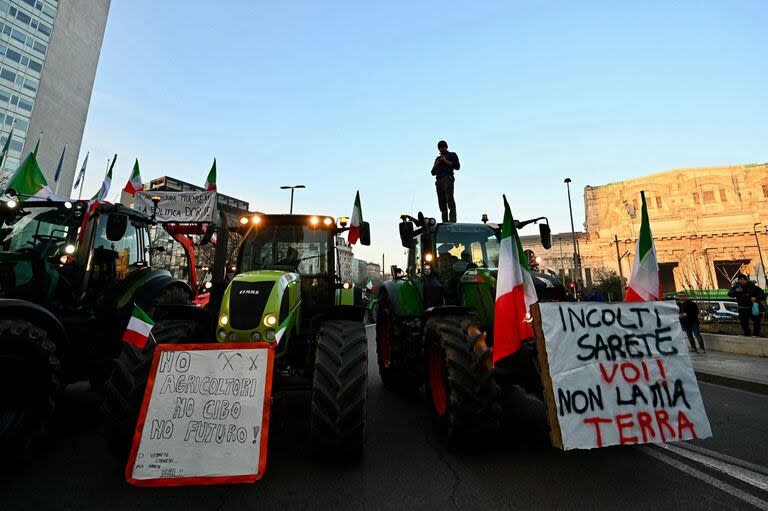 Un agricultor italiano sube a un tractor en el centro de Milán durante una protesta el 1 de febrero de 2024. Un cartel (izq.) que dice “Sin agricultura, sin comida, sin futuro”. Al igual que otros países europeos, Italia ha sido testigo de semanas de crecientes protestas. (Foto de GABRIEL BOUYS / AFP)