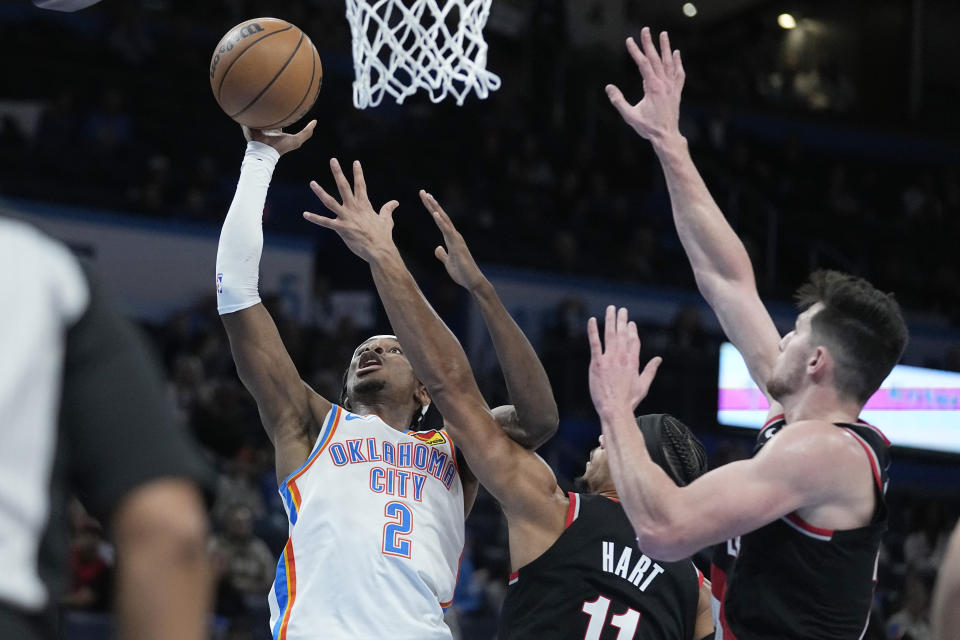 Oklahoma City Thunder guard Shai Gilgeous-Alexander (2) shoots in front of Portland Trail Blazers guard Josh Hart (11) and =ppo24=, right, in the second half of an NBA basketball game Monday, Dec. 19, 2022, in Oklahoma City. (AP Photo/Sue Ogrocki)