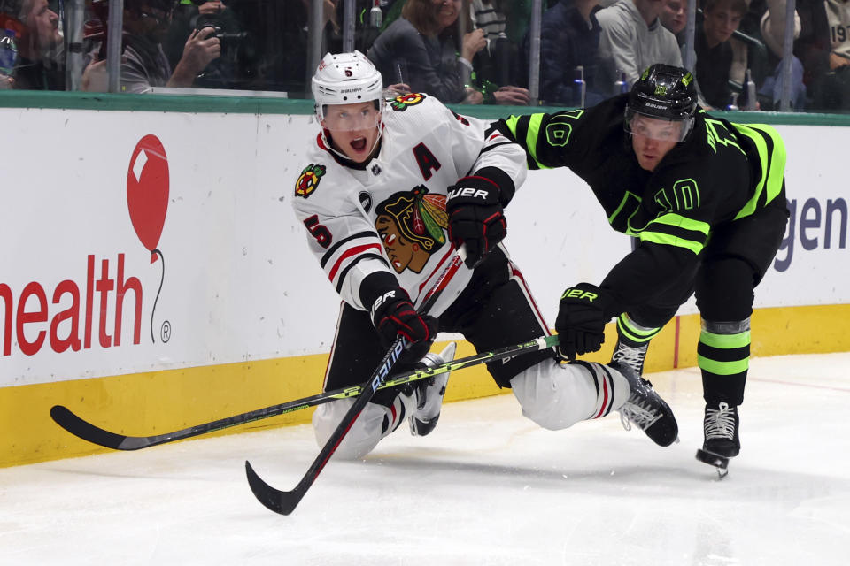 Chicago Blackhawks defenseman Connor Murphy (5) and Dallas Stars center Ty Dellandrea (10) battle for the puck in the first period of an NHL hockey game Sunday, Dec. 31, 2023, in Dallas. (AP Photo/Richard W. Rodriguez)