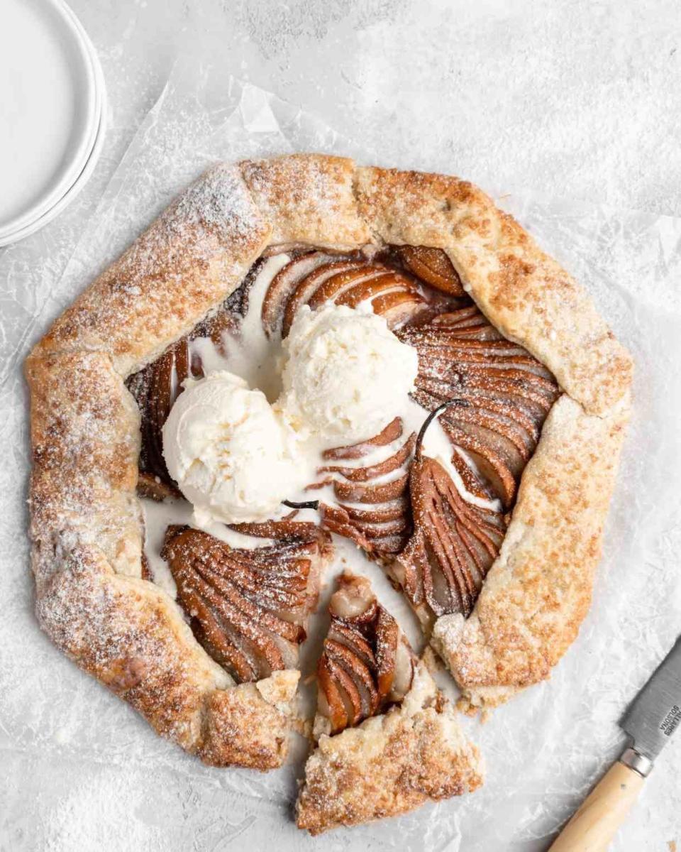 A galette filled with sliced pears and topped with vanilla ice cream.