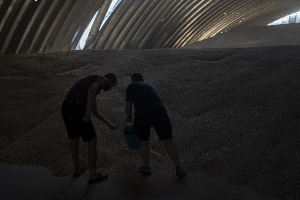 Two workers collect samples in a warehouses partially damaged in Russian missile attacks at a grain facility in Pavlivka, Ukraine, Saturday, July 22, 2023. The collapse of the Black Sea grain deal and a series of missile strikes on Ukrainian grain silos and ports have left farmers with few options to export their grain — and all of them are getting more expensive. (AP Photo/Jae C. Hong)