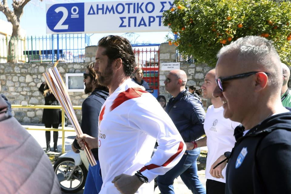 US actor Gerard Butler runs as a torchbearer during the Olympic torch relay of the 2020 Tokyo Olympic Games in the southern Greek town of Sparta, Friday, March 13, 2020. Greece's Olympic committee says it is suspending the rest of its torch relay for the Olympic flame due to the "unexpectedly large crowd" that gathered to watch despite repeated requests for the public to stay away to prevent the spread of the new coronavirus. (AP Photo)