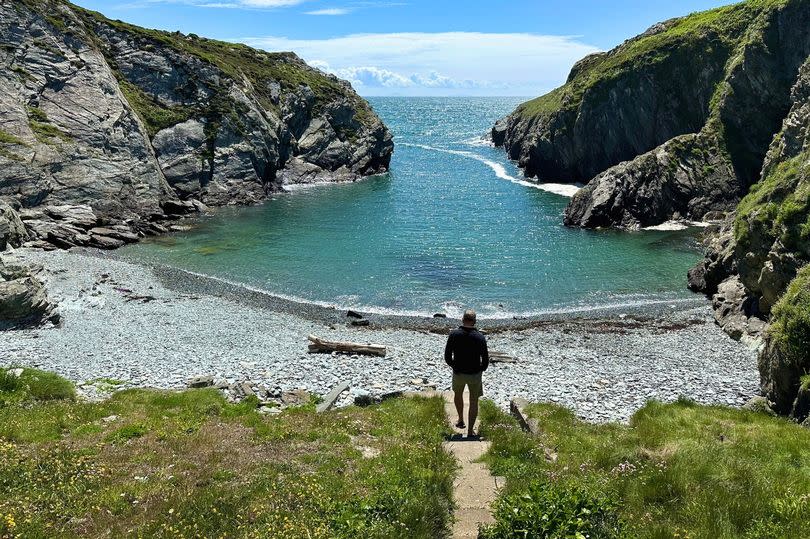 A wide shot showing a person walking down to the shingle beach