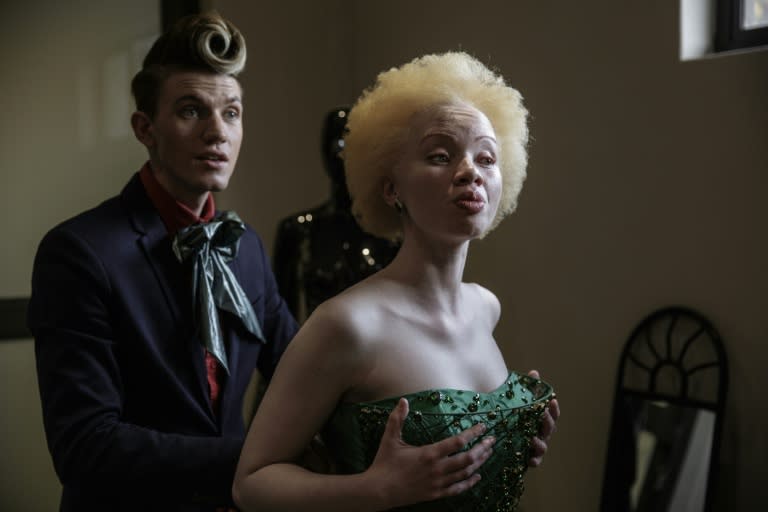 South African lawyer and fashion model Thando Hopa (R) tries on an evening dress by fashion designer Gert-Johan Coetzee at his workshop on June 13, 2015 in Johannesburg