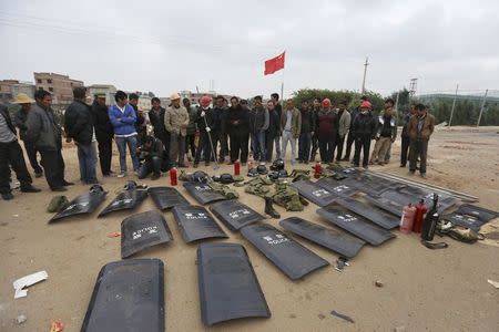 Villagers stand behind shields taken from police injured during clashes at Fuyou village in Jinning county, Kunming, Yunnan province, October 15, 2014. REUTERS/Wong Campion