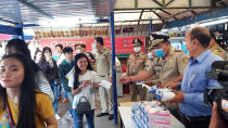 In this Jan. 27, 2020, photo provided by the Poipet International Checkpoint, government officials distribute face masks to tourists during a launch of a plan to distribute a million masks to travelers arriving at the checkpoint with Thailand as a safety precaution against the coronavirus infection in Poipet, northeastern Cambodia. China on Tuesday reported 25 more deaths from a new viral disease, as the U.S. government prepared to fly Americans out of the city at the center of the outbreak. (Poipet International Checkpoint via AP)