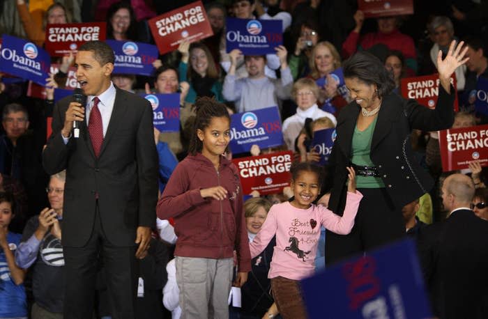 Barack Obama speaks at a podium with daughters Sasha and Malia and wife Michelle at a campaign event
