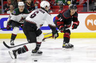 Carolina Hurricanes' Seth Jarvis (24) passes the puck past Arizona Coyotes' Jakob Chychrun (6) during the second period of an NHL hockey game in Raleigh, N.C., Sunday, Oct. 31, 2021. (AP Photo/Karl B DeBlaker)