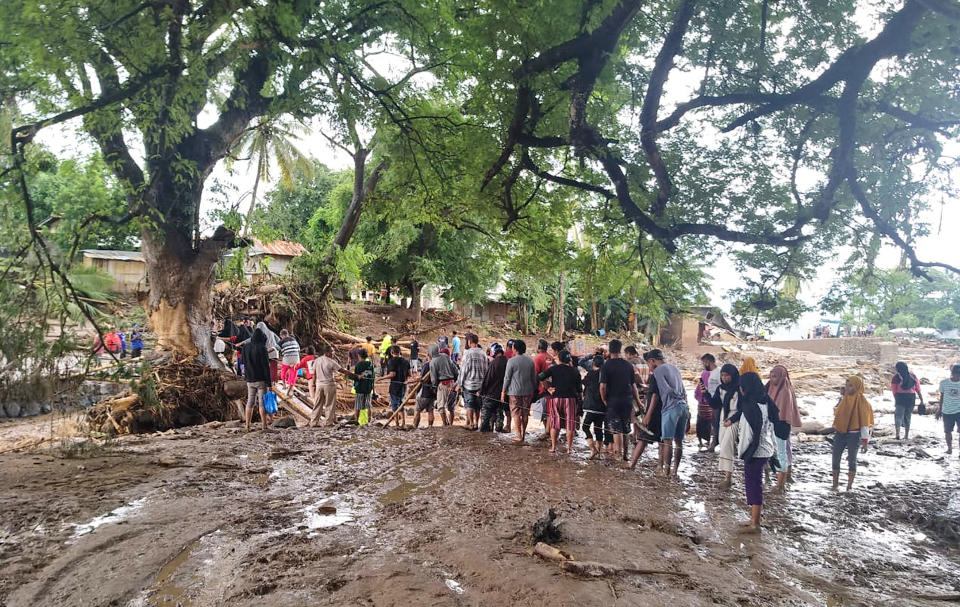 People queue up to cross a makeshift bridge at a village affected by floods on Adonara Island, East Flores, Indonesia, Monday, April 5, 2021. Multiple disasters caused by torrential rains in eastern Indonesia and neighboring East Timor have left a number of people dead or missing as rescuers were hampered by damaged bridges and roads and a lack of heavy equipment Monday. (AP Photo/Rofinus Monteiro)