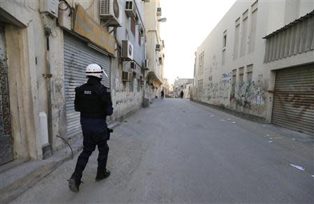 A riot police officer patrols a street in the early hours of the morning after police cleared up road blocks set up by anti-government protesters in the village of Karanna, west of Manama, February 13, 2014. REUTERS/Hamad I Mohammed