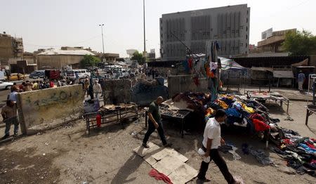 Men walk past the site of a suicide bomb attack in Baghdad, Iraq, September 17, 2015. At least 12 people were killed when three bombs went off in mainly Shi'ite neighborhoods in central Baghdad on Thursday, security and medical sources said. REUTERS/Ahmed Saad