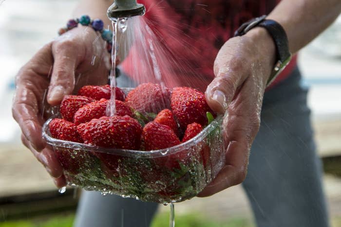 Someone washing a bowl of strawberries