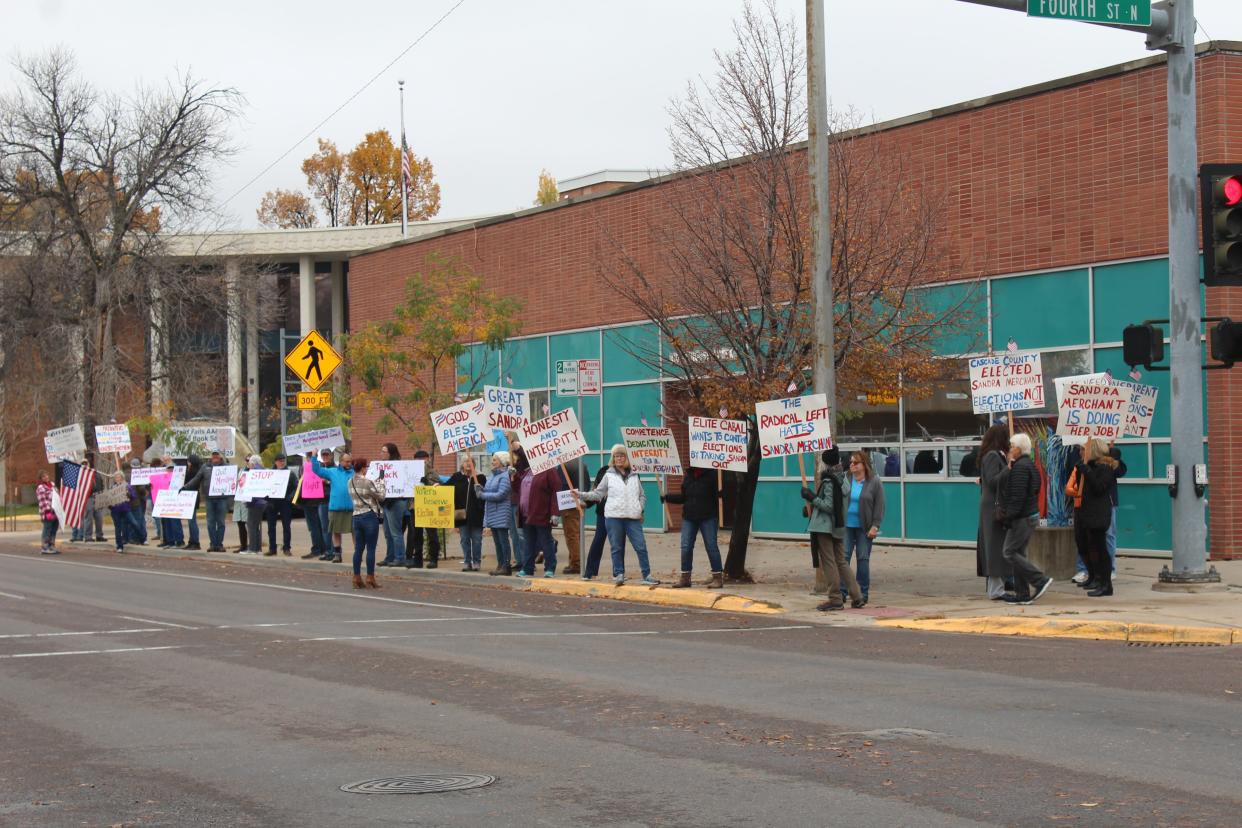 Close to 40 demonstrators assembled outside the Cascade County Elections Office Monday to both support Clerk and Recorder Sandra Merchant and to demand her ouster from the elections office