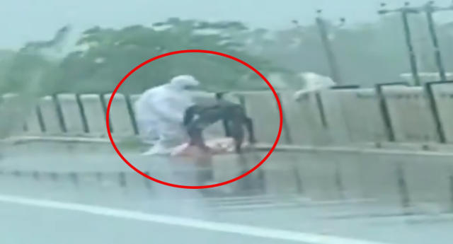 Two men are seen picking up the body of a Covid patient before throwing it off a bridge. 