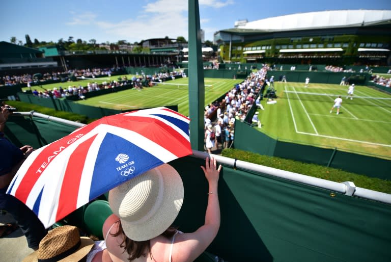 Spectators shelter from the sun beneath a Union flag-themed umbrella as they watch a match on day three of Wimbledon, on July 1, 2015