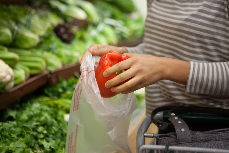 Coles shopper places capsicum into plastic produce bag