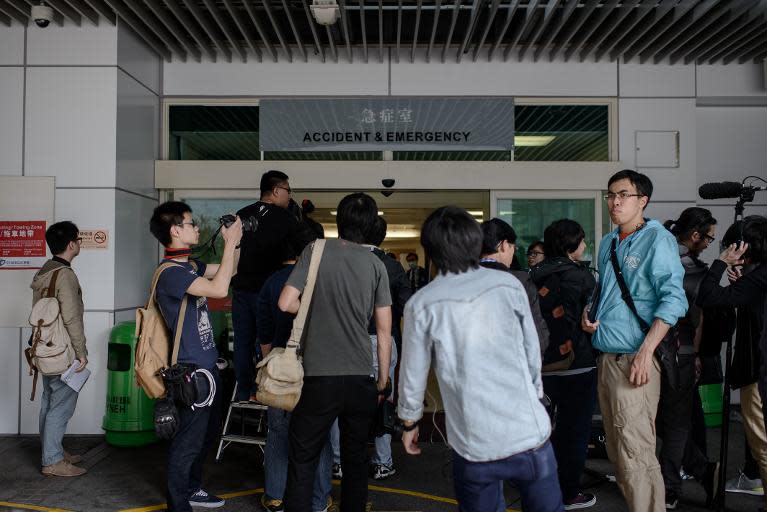 Members of the press wait at the entrance of the hospital where the former editor of a liberal Hong Kong newspaper was admitted after being attacked with a meat cleaver on February 26, 2014