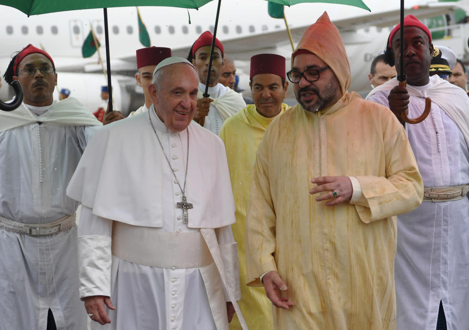 Pope Francis, left is greeted by Morocco's King Mohammed VI, centre upon disembarking from his plane at Rabat-Sale International Airport near the capital Rabat, Saturday, March 30, 2019. Pope Francis has arrived in Morocco for a trip aimed at highlighting the North African nation's tradition of Christian-Muslim ties, while also letting him show solidarity with migrants at Europe's door and tend to a tiny Catholic flock. (Fadel Senna/Pool Photo via AP)