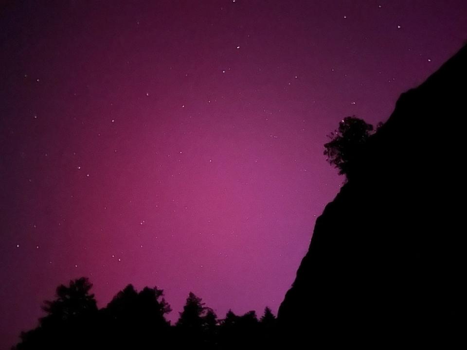 pink starry night sky with silhouette of hillside and trees in the foreground